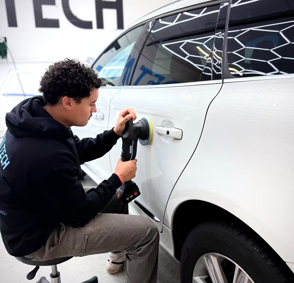 Detail Tech technician machine polishing a white sedan door panel