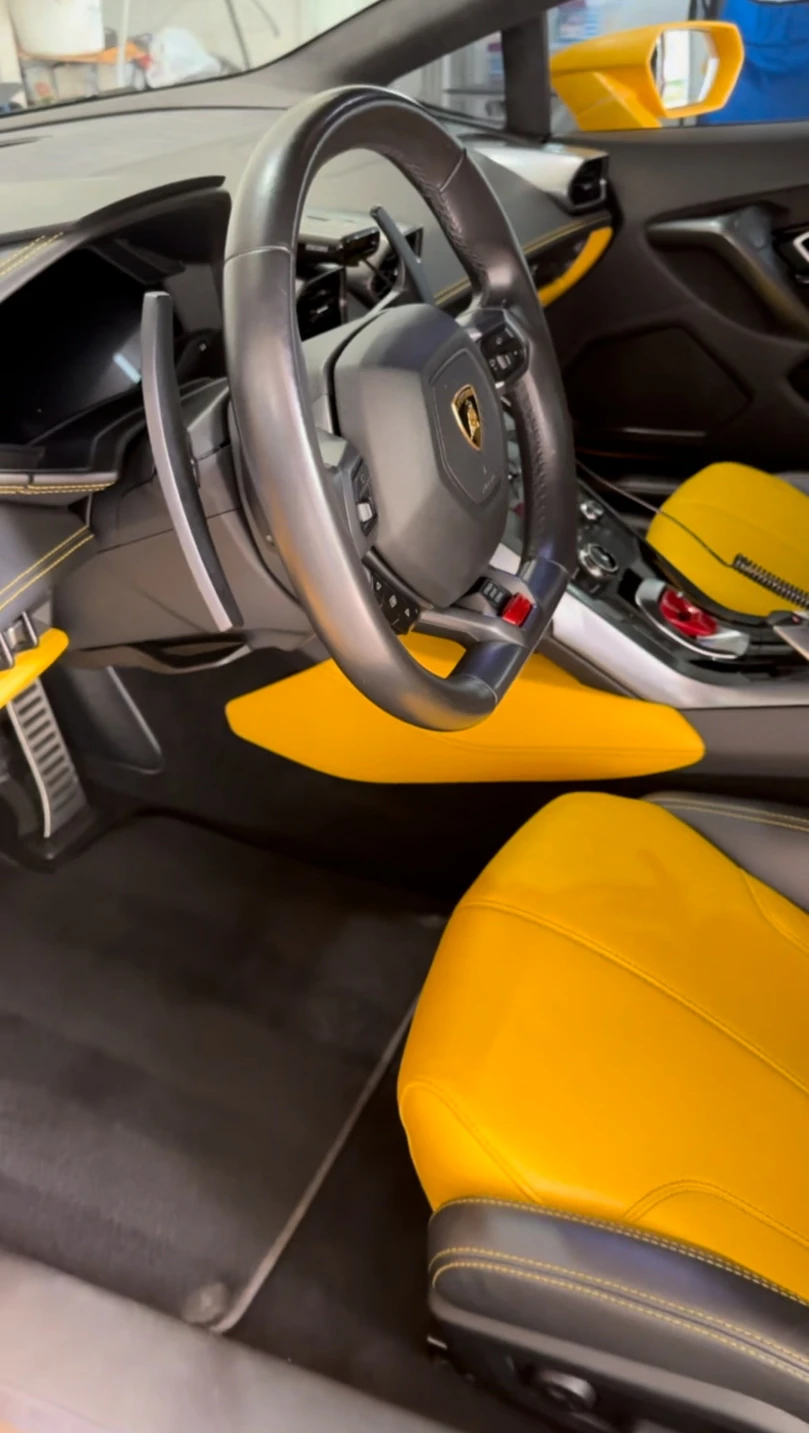 Yellow leather driver's seat and steering wheel of a Lamborghini Huracan after detailing