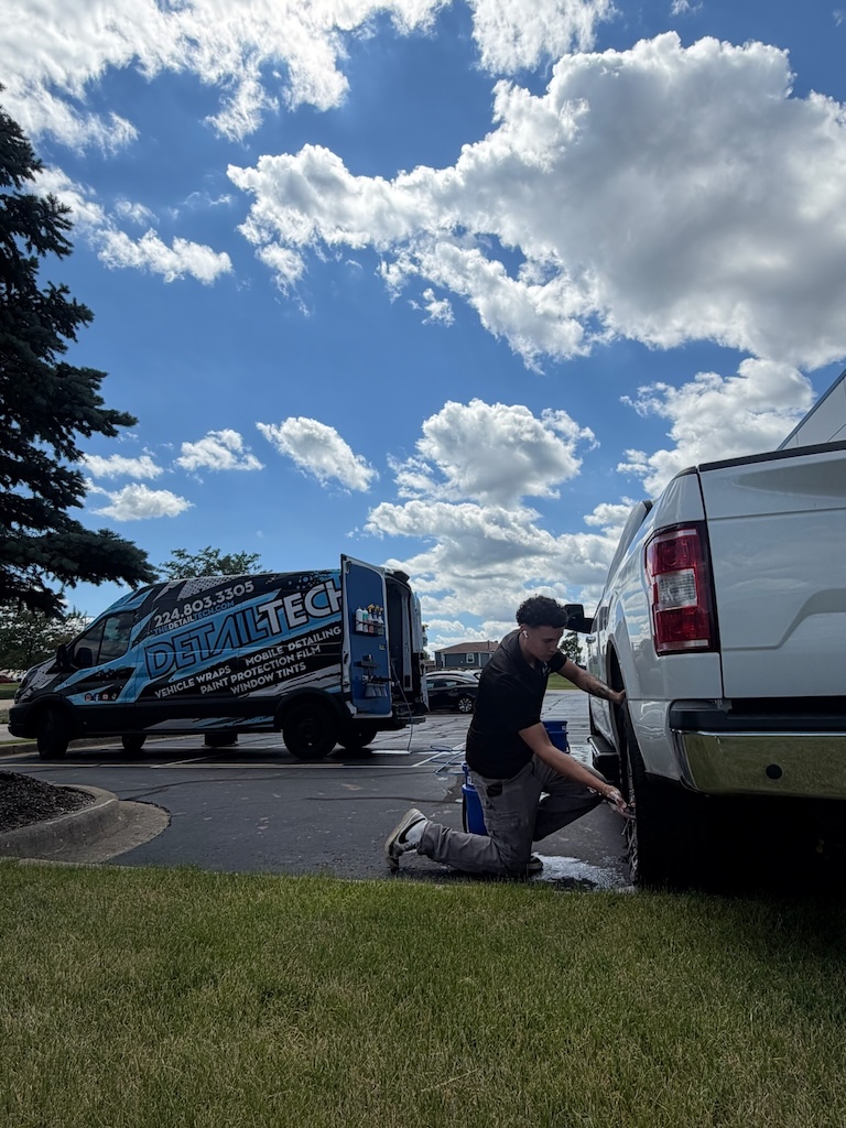Detail Tech technician detailing a white pickup truck beside the mobile van