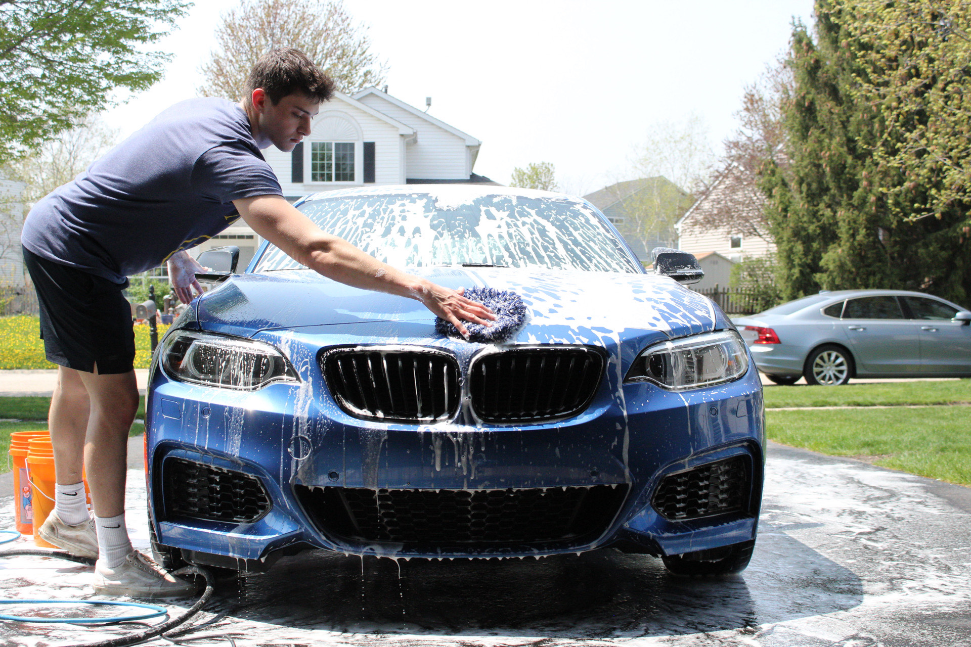 Detail Tech mobile detailing a blue BMW in a customer's driveway