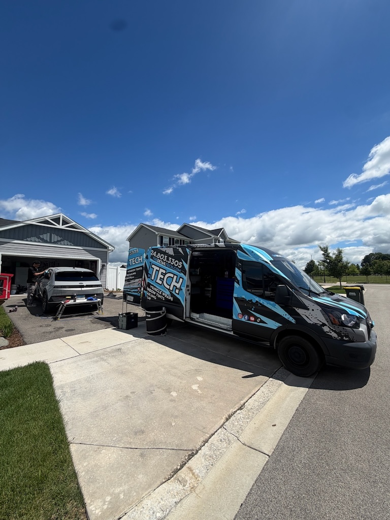 Detail Tech mobile van with doors open while a technician details a car in the driveway