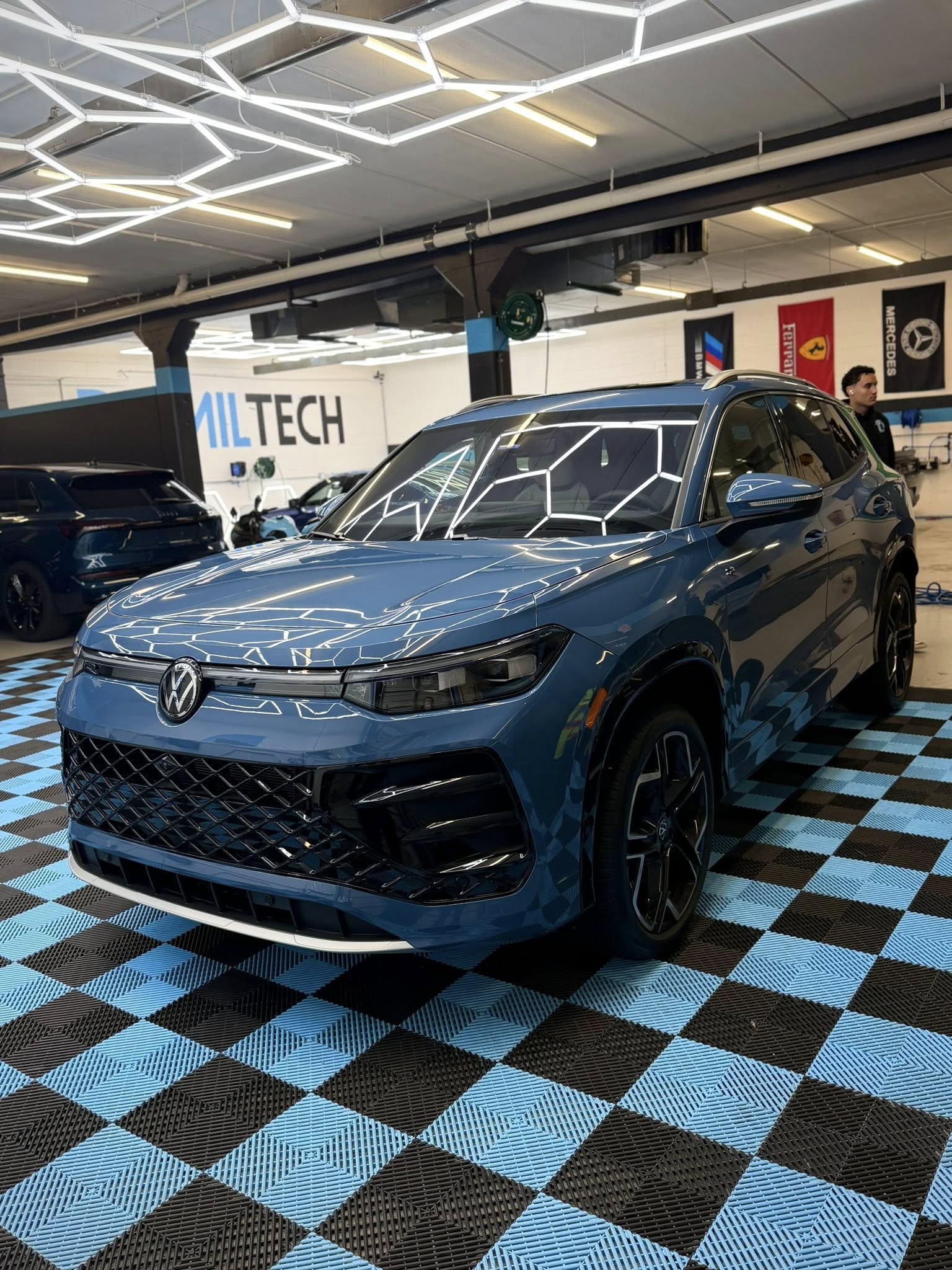 Blue Volkswagen Tiguan under the hex lights at the Detail Tech shop