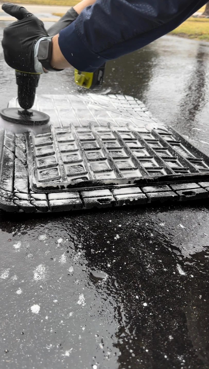 Detail Tech technician machine scrubbing a foamy vehicle floor mat clean
