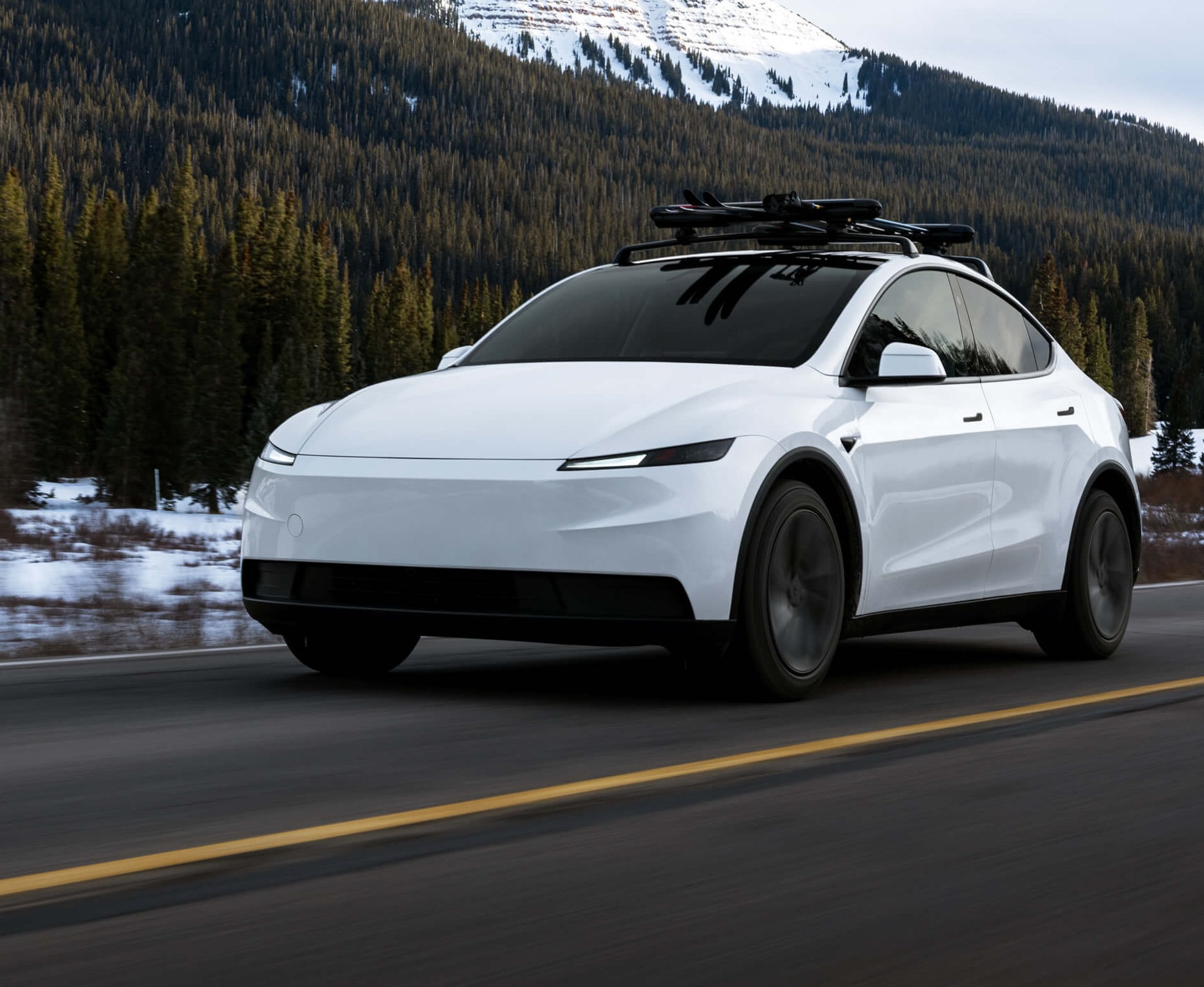 White Tesla Model Y on a snowy mountain road