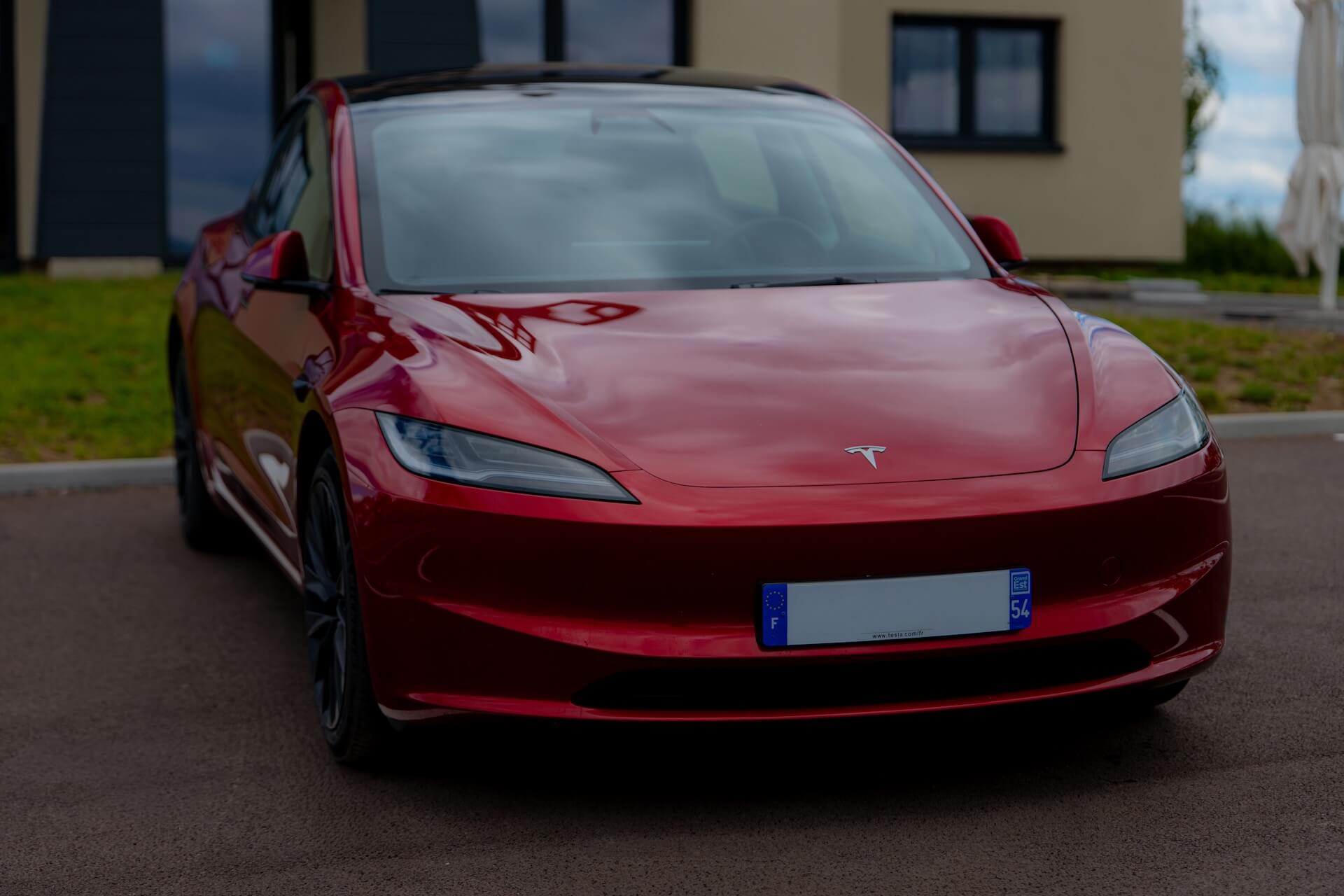 Red Tesla Model S on a tree-lined road after protection work