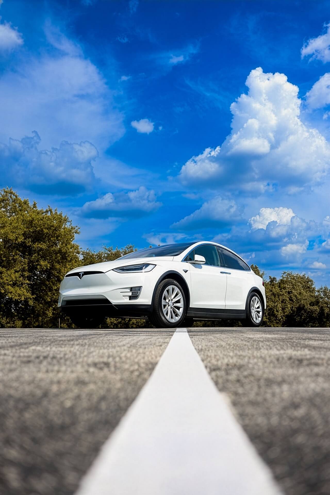 White Tesla Model X on the road under a blue sky