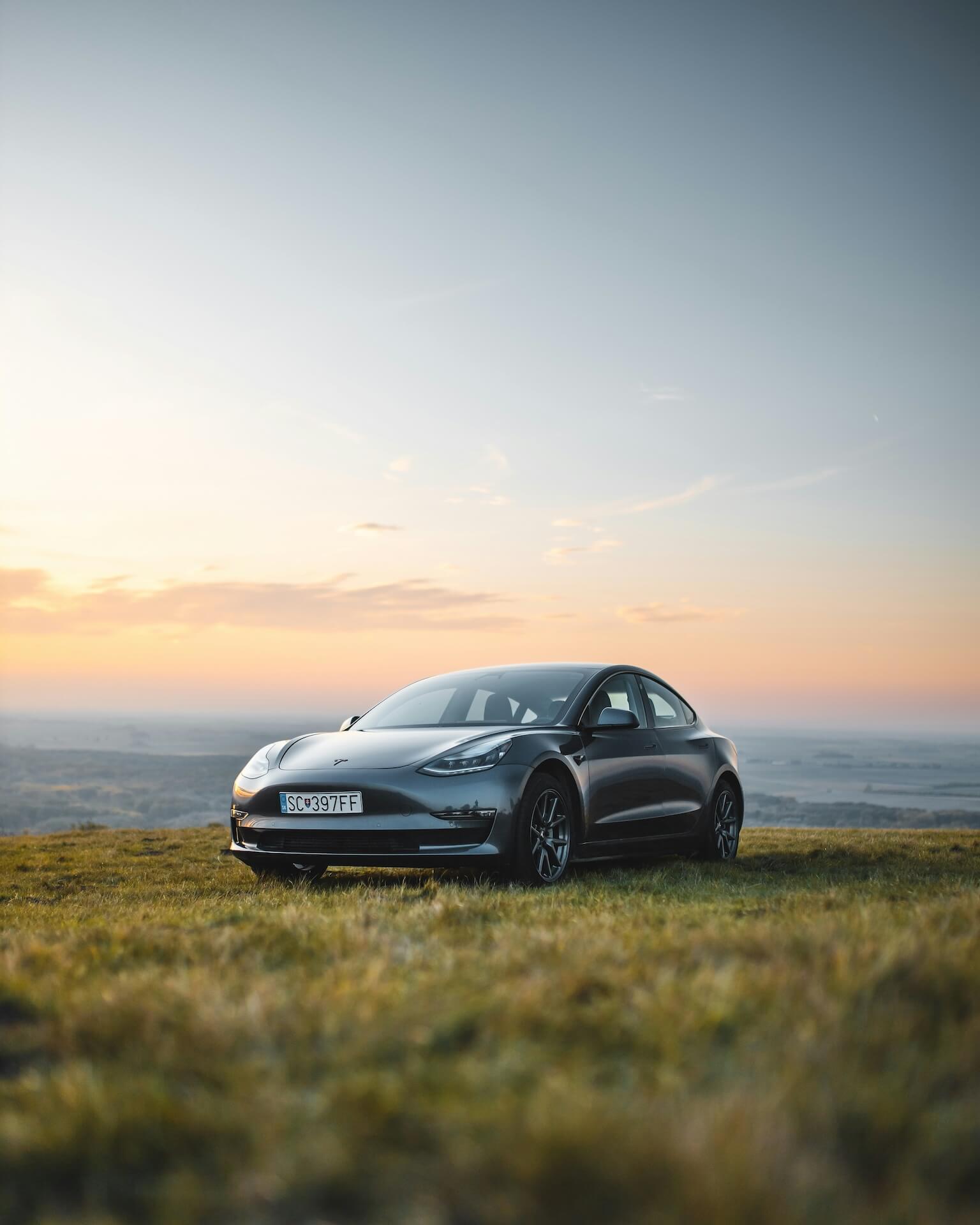 Grey Tesla Model 3 with tinted windows at sunset
